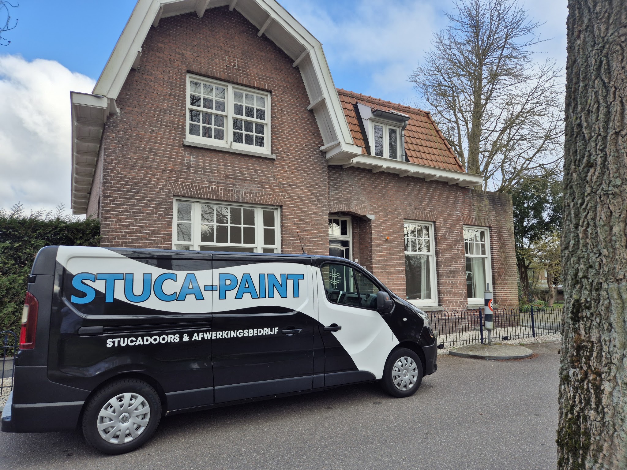 De zwart-witte bus van Stuca-Paint, stucadoors en afwerkingsbedrijf, voor een klus