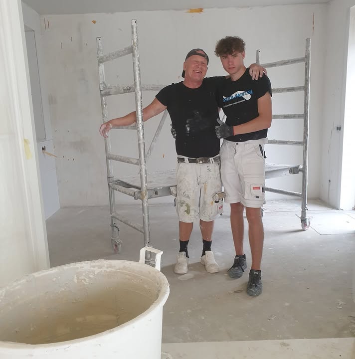 Ruud en Mike Gijzen in werkkleding naast de steiger in een pas gestucte ruimte